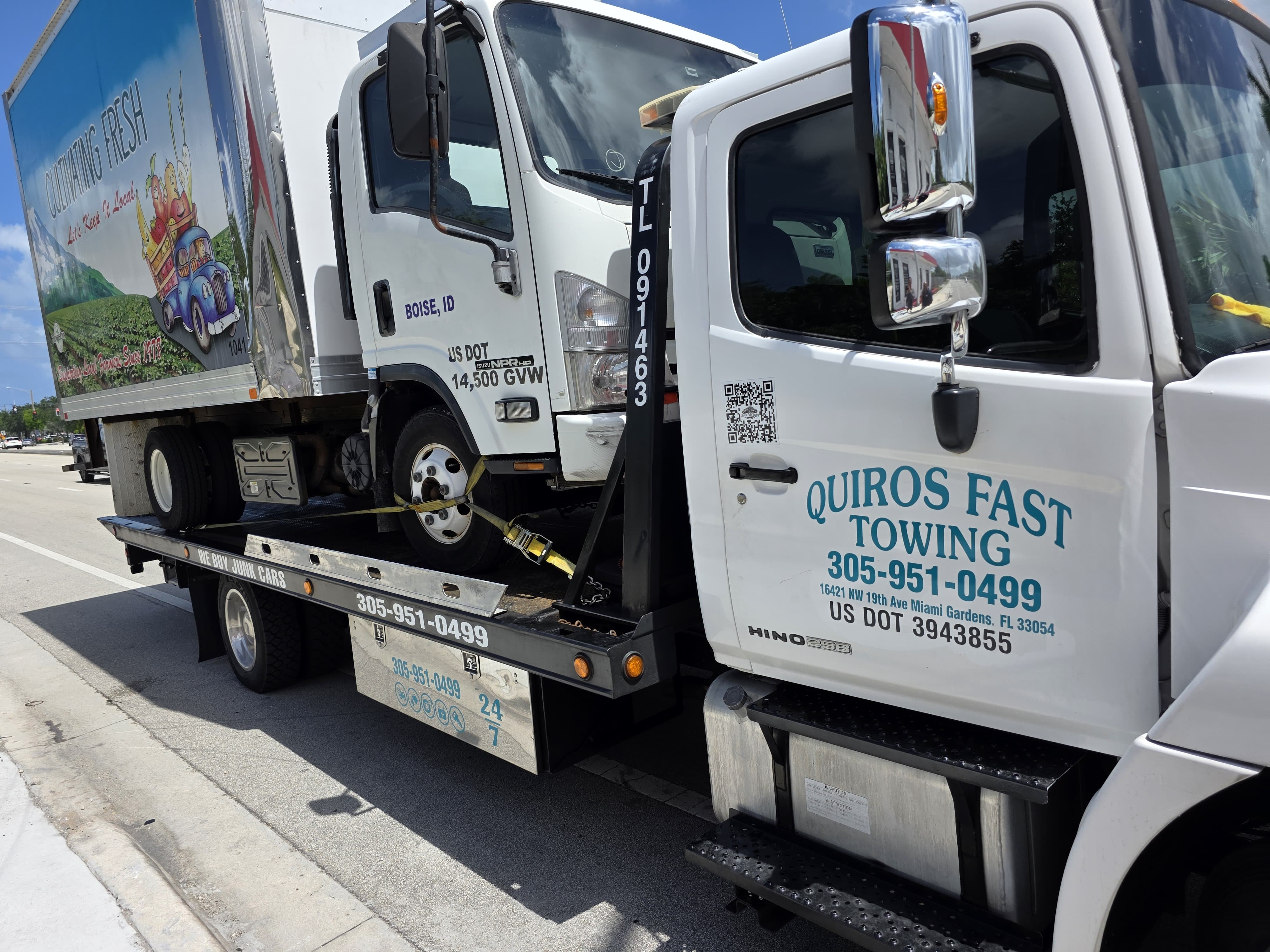 Quiros Fast Towing flatbed hauling an Isuzu NPR box truck