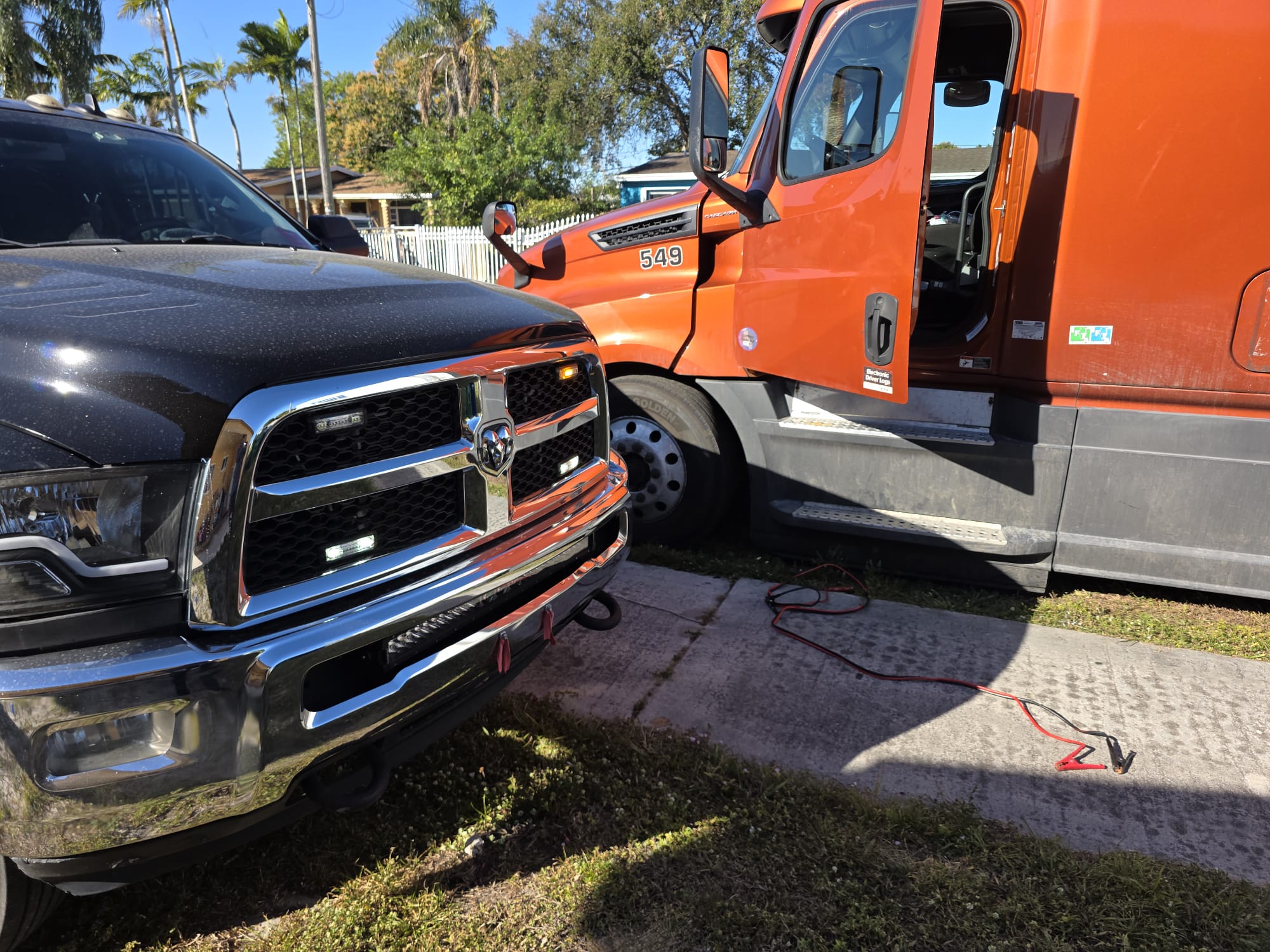 Quiros Ram jump-starting an orange Freightliner Cascadia semi-truck