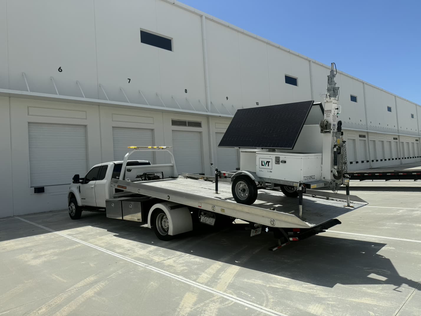 Ford F-450 flatbed loading an LVT solar-powered surveillance trailer