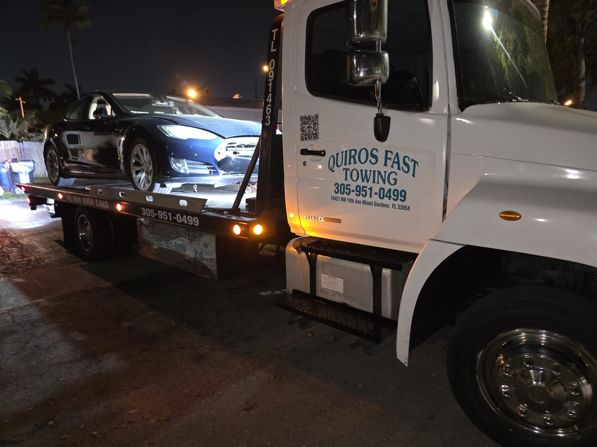 Tesla Model S on a Quiros flatbed at night after a front-end incident